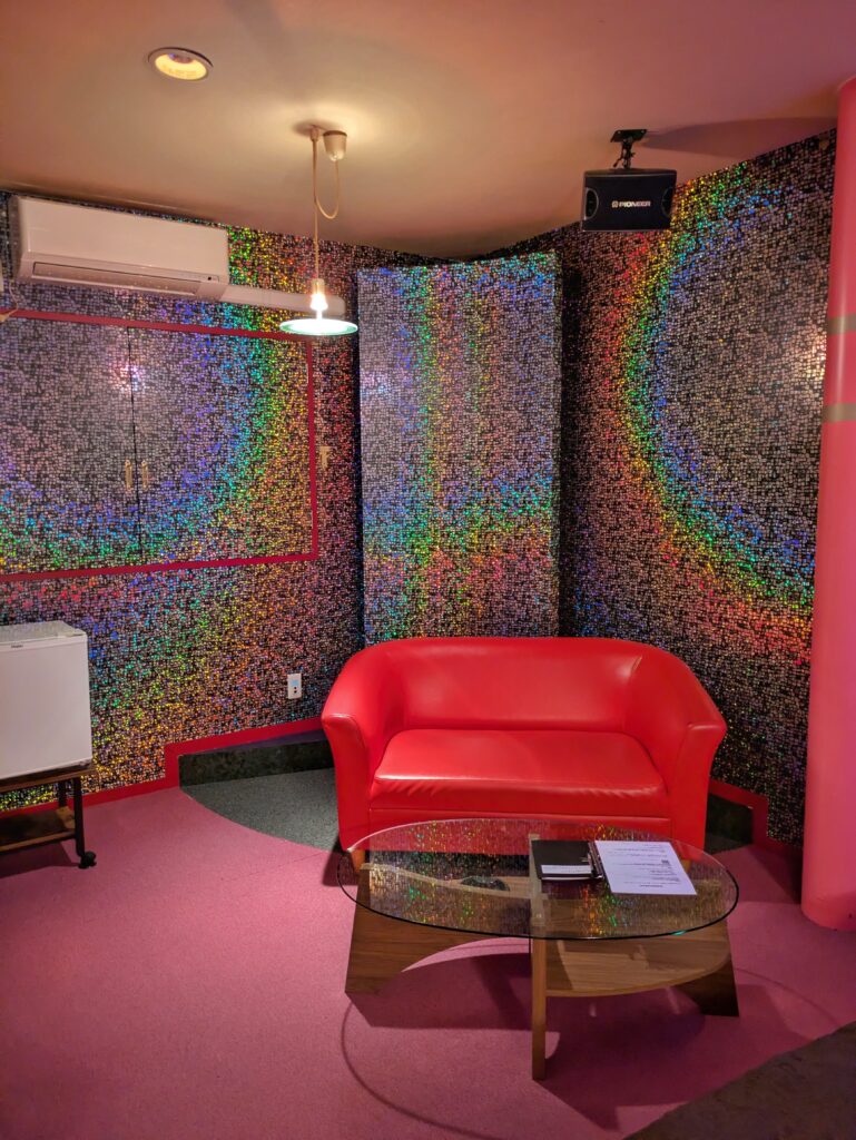 網走 Hotel ARUN 客房內部:炫彩馬賽克霓虹牆面與鮮紅雙人沙發