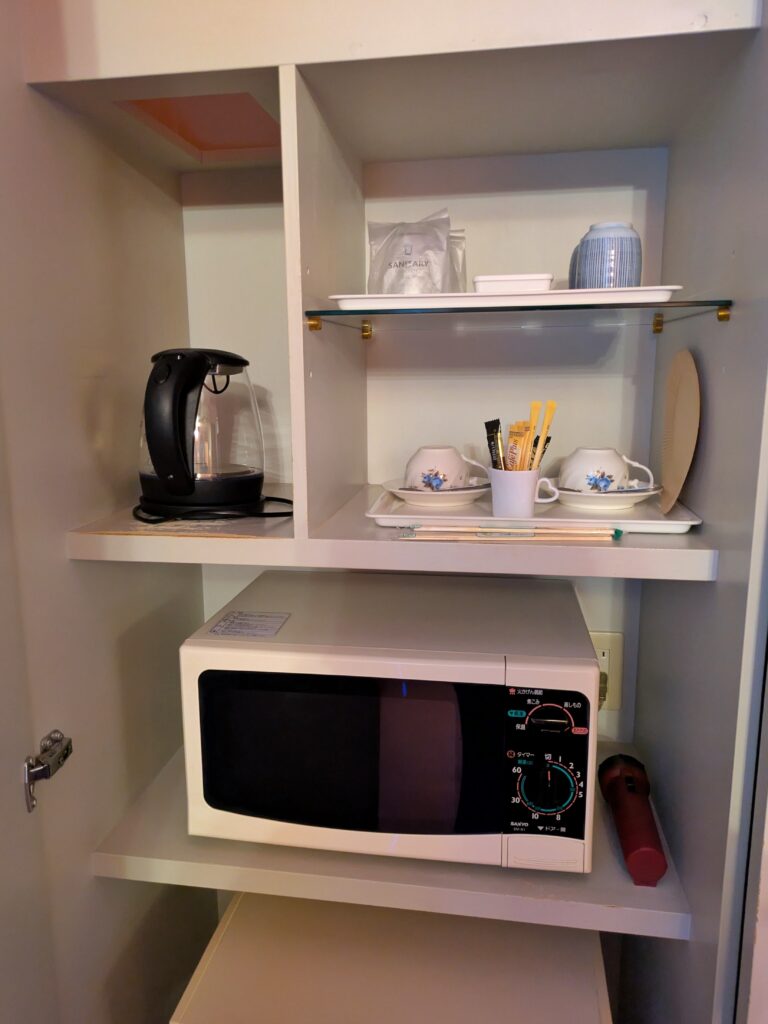 Hotel ARUN 客房電器配置:微波爐、快煮壺、餐具與電器櫃